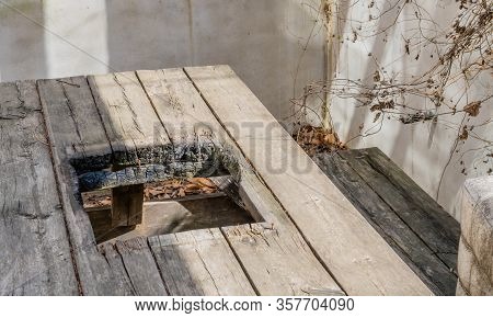 Picnic Table With Charred Square Hole In Center For Barbeque Grill.