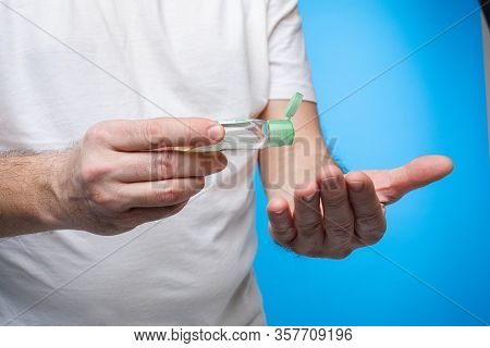 Man In White T-shirt, Black Jeans Stands With Antiseptic And Desinfects His Hands With Anticeptic Is