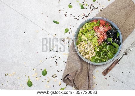 Salted Salmon Poke Bowl With Avocado, Sea Cale, Cucumber, Sesame Seeds And Bean Sprouts On Grey Back