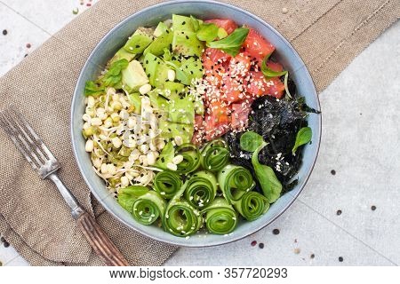 Salted Salmon Poke Bowl With Avocado, Sea Cale, Cucumber, Sesame Seeds And Bean Sprouts On Grey Back