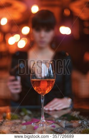 Blissful Woman Silhouette With A Gun. In Front Of Her Is A Glass Of Wine On The Table.