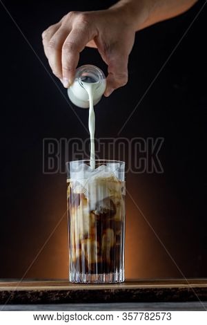 Iced latte with dark background on a wooden table. Milky iced coffee