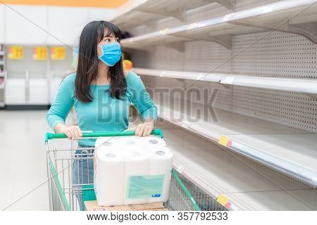 Asian Woman Looking At Supermarket Empty Toilet Paper Shelves Amid Covid-19 Coronavirus Fears, Shopp