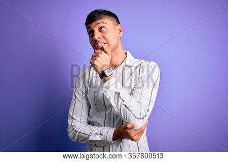 Young handsome hispanic man wearing elegant business shirt standing over purple background Thinking worried about a question, concerned and nervous with hand on chin