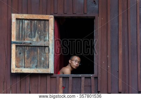 Nyaungshwe, Myanmar - December 26, 2019: A Young Monk Looking Out Window In Shwe Yanp Yay Monastery.