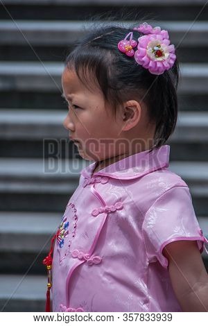 Shanghai, China - May 4, 2010: Closeup Of Young Girl In Pink Dress And Hair Speld, With Gray Steps I