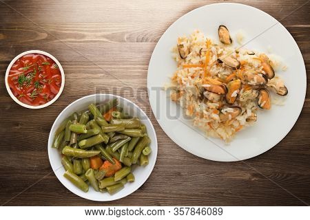 Rice With Mussels And Carrots On A White Plate. Rice With Mussels And Carrots On A Borwn Wooden Back