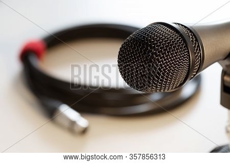 Closeup Of Vocal Microphone Head With Black Grille And Cable With Xlr Connector In Background Isolat