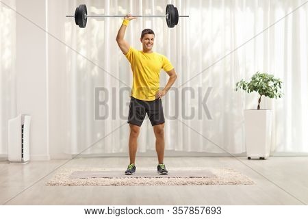 Full length portrait of a young fit man lifting weigths at home