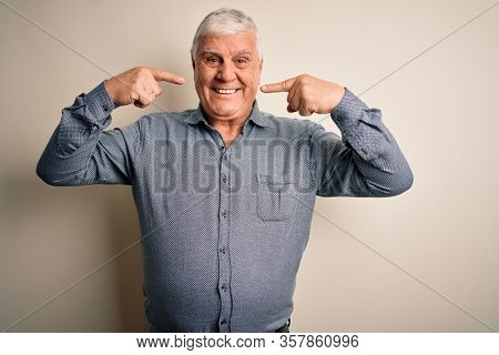 Senior handsome hoary man wearing casual shirt standing over isolated white background smiling cheerful showing and pointing with fingers teeth and mouth. Dental health concept.