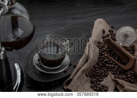 Coffee Style, Cup Of Coffee And Coffee Beans Roating With Old Wooden Scoop And Coffee Beans Around O