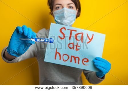 Woman In A Medical Mask With A Temperature. Holding A Thermometer In His Hands. Mild Condition Of A 