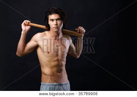 Imagen de hombre semidesnudo con bate mirando a cámara