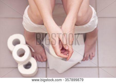 Man Is Sitting On The Toilet. Constipation Or Diarrhea. A Lot Of Toilet Paper On The Floor. Man Hold