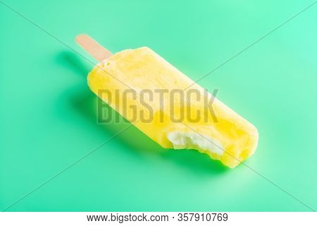Yellow Popsicle With A Big Bite On A Light Green Background