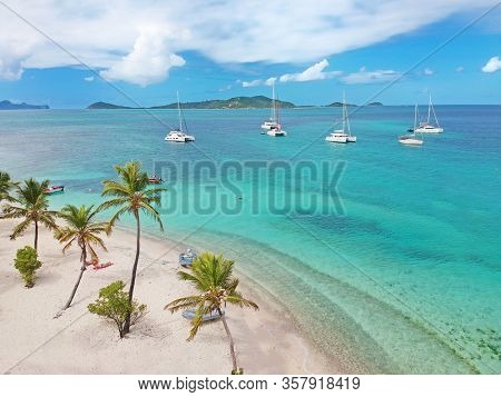 Aerial view of Petit Rameau tropical Caribbean Island beach, sailing catamarans and boats from above 