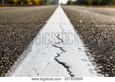 Old Asphalt Road. Driving On An Empty Road. Cracked White Line On The Asphalt Road. Shallow Depth Of