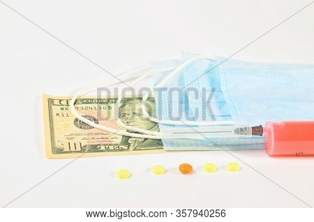 Syringe With Vaccine And Pills On The Background Of Banknotes And Medical Masks