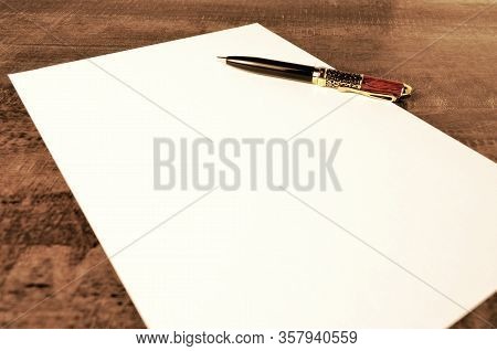 Pen With Gold And Wooden Trim On A White Sheet Of Paper