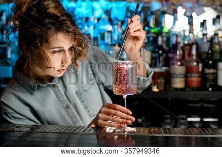 Lady Barman Attentively Decorates Glass With Rose Cocktail By Piece Of Green Plant.