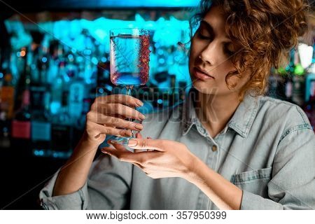 Beautiful Lady Barman Holds Glass In Her Hands And Looks At It.
