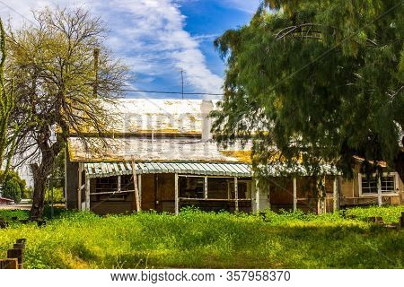 Old Tin Roof Home In Disrepair And Overgrown Yard