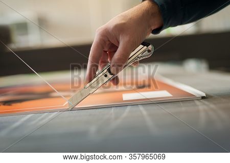 Close-up Of Hand With Skalpel. Worker Cut Paper In Printshop