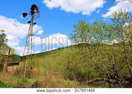 Historical Rustic Windmill From The 1800s On Abandoned Ranchlands Surrounded By A Riparian Woodland 