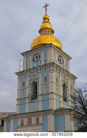 Close-up View Of High Bell-tower With Clock And Golden Dome. Fantastic Soft Clouds In The Background