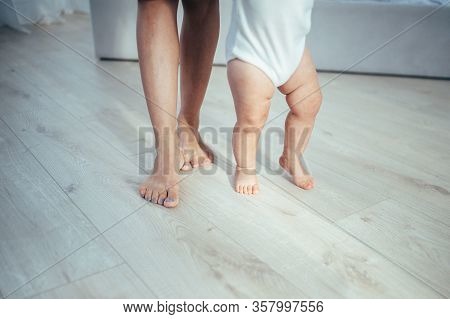 The Bare Feet Of The Child And Mother Are On The Floor