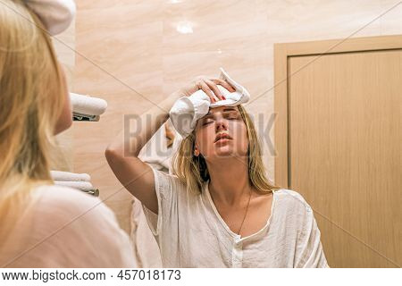 Headache, Migraine. Portrait Reflection In Mirror Of Young Girl Making Cold Compress With Towel On H