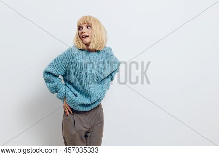 Horizontal Photo Of A Nice, Sweet Woman In A Soft, Blue Sweater Standing On A White Background And P