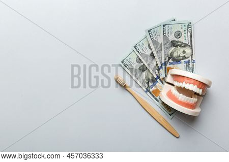 Closeup Model Of A Human Jaw With White Teeth And Dollar Bill. Dentistry Conceptual Photo. Prostheti
