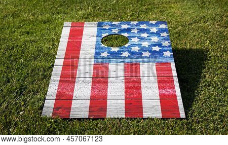 Close Up Of An American Flag Corn Hole Game Board On A Grass Field.