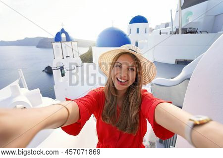 Excited Traveler Girl Taking Selfie Photo In Santorini On Sunset. Young Woman Having Fun In Oia Pict