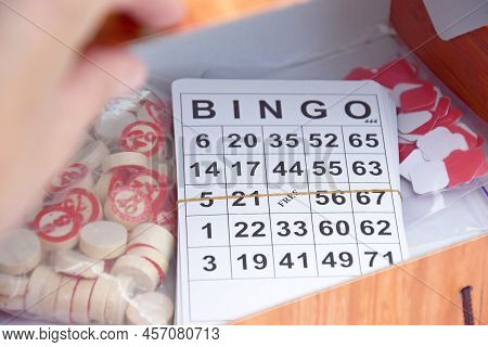 Many Wooden Chips With Numbers And Cards For A Board Game Of Bingo Or Lotto On A Light Background.