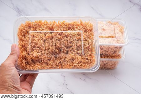 Hand Holding A Box Of Sweet And Sour Crispy Noodles (or Mee Krob In The Thai Language) On A Marble B