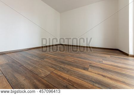 Laminated Wood Floor With White Wall. Empty Room With Floating Laminate In New Apartmen