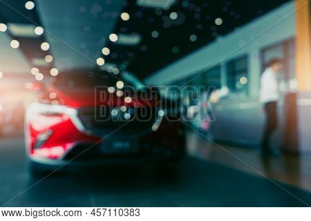 Blurred Photo New Red Car Parked In Showroom. Car Dealership Office. Car Parked In Showroom With Car