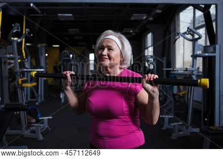 Happy Healthy Senior Woman Exercising With Bodybar At The Gym