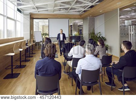 People Working In Joint Office Listen To Male Manager Who Talks About Companys Corporate Program.