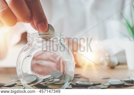 Businessman Holding Lightbulb On Coins Stacking On Desk With Note For Planning Money Finance.saving 