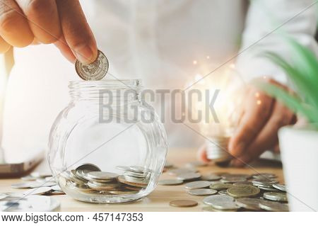 Businessman Holding Lightbulb On Coins Stacking On Desk With Note For Planning Money Finance.saving 