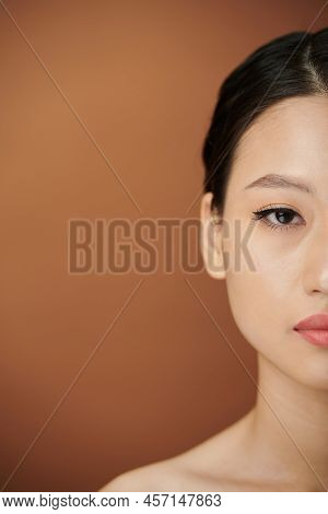 Half Face Of Young Asian Woman With Eye Liner And Lip Tint Looking At Camera