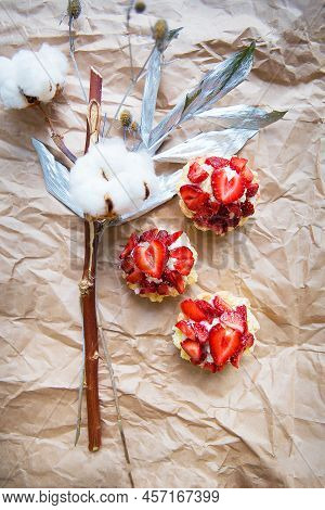 Beautiful Cupcakes With Strawberries Along With A Branch On Kraft Paper.