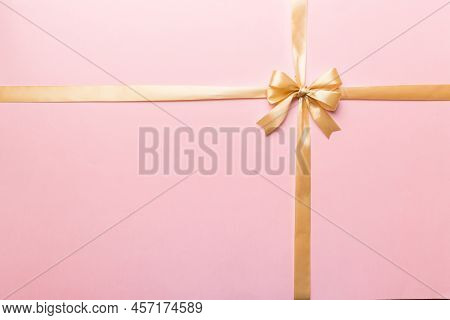 Top View Of Gold Ribbon Rolled And Yellowbow Isolated On Colored Background. Flat Lay With Copy Spac