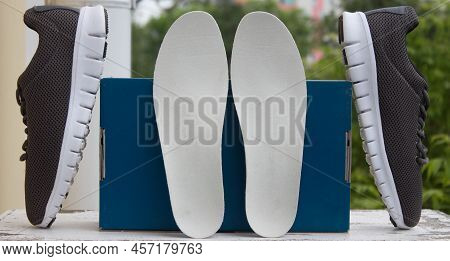 Leather Orthopedic Insoles In Front Of Blue Box And Pair Of Sport Shoes. Outdoors.
