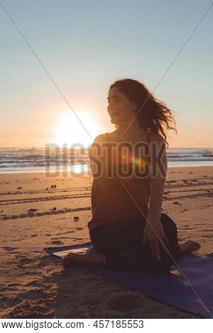 Silhouette Of A Woman On The Beach Practicing A Stretching Exercise At Sunset. Vertical