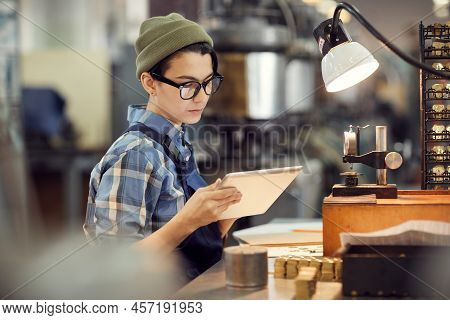 Serious Busy Hipster Female Worker Of Watch Factory Sitting At Desk And Reading Online Instruction O