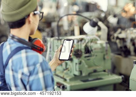 Rear View Of Hipster Machine Operator Standing At Factory And Controlling Factory Processes With Sma